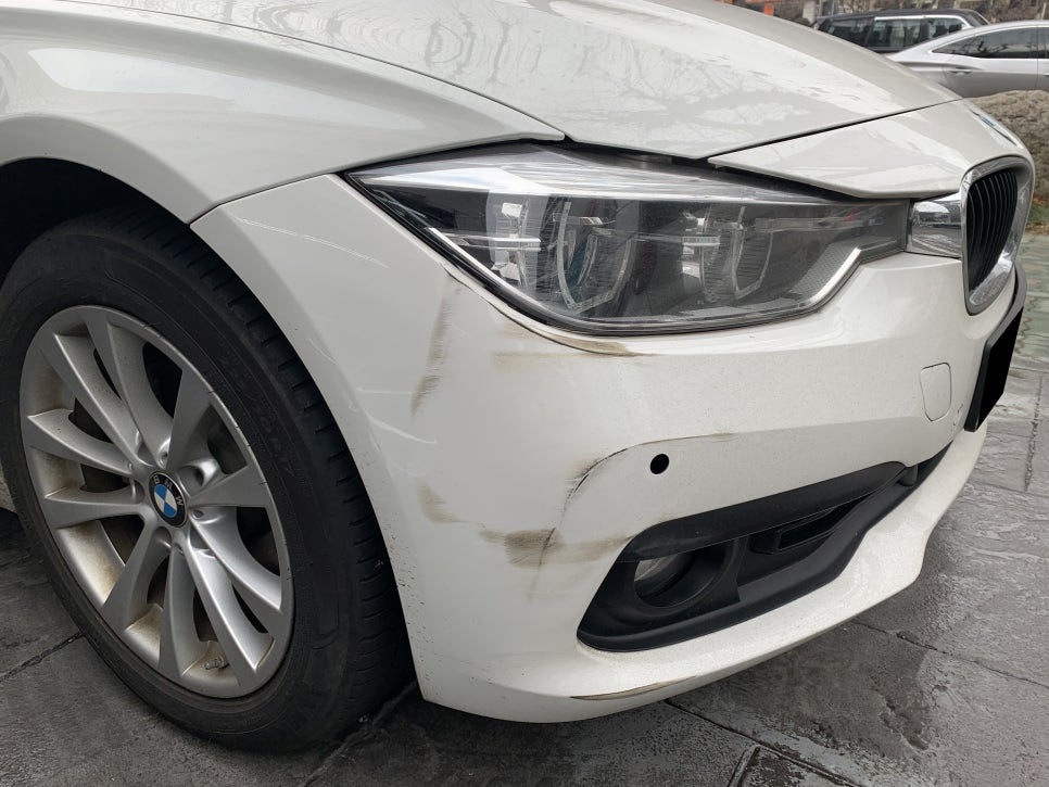 알파인 화이트 색상의 BMW 320d 앞 범퍼 운전석 및 조수석 파손 상태, 조수석 전방 감지 센서가 안으로 밀려 들어간 모습